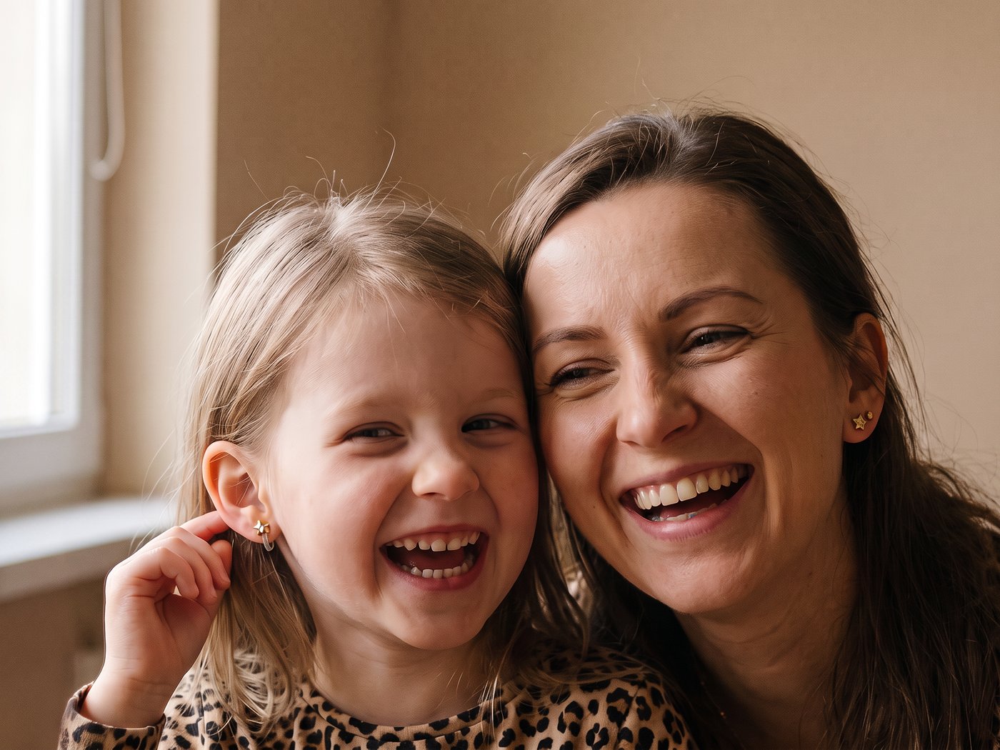 Mama i córka śmieją się, córka w kolczykach na klips